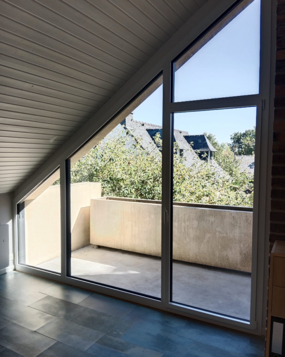 Menuiserie aluminium K•LINE trapézoïdale installée sous une toiture inclinée près de Rennes.